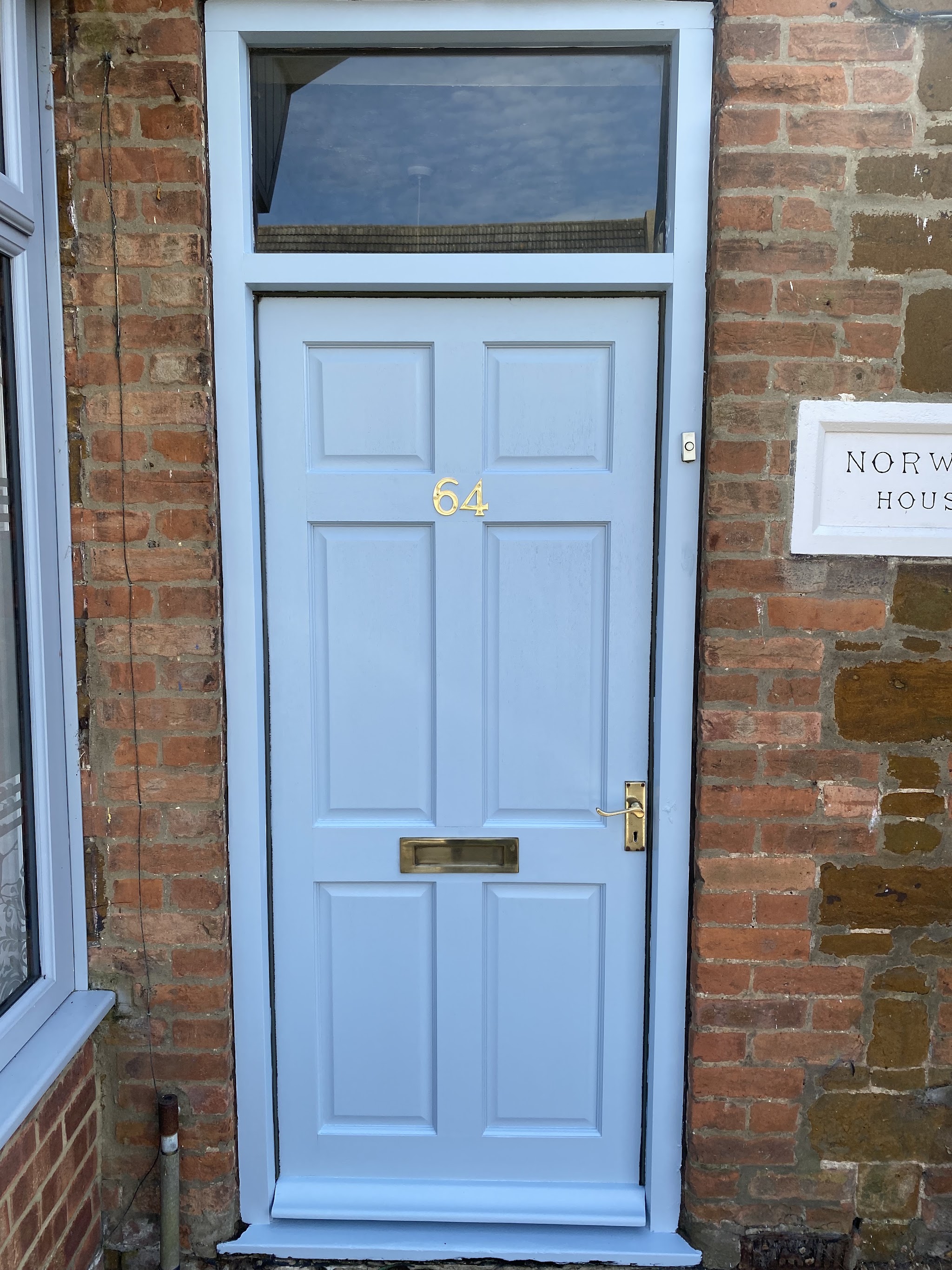 Pale blue six-panel front door set in brick and carrstone