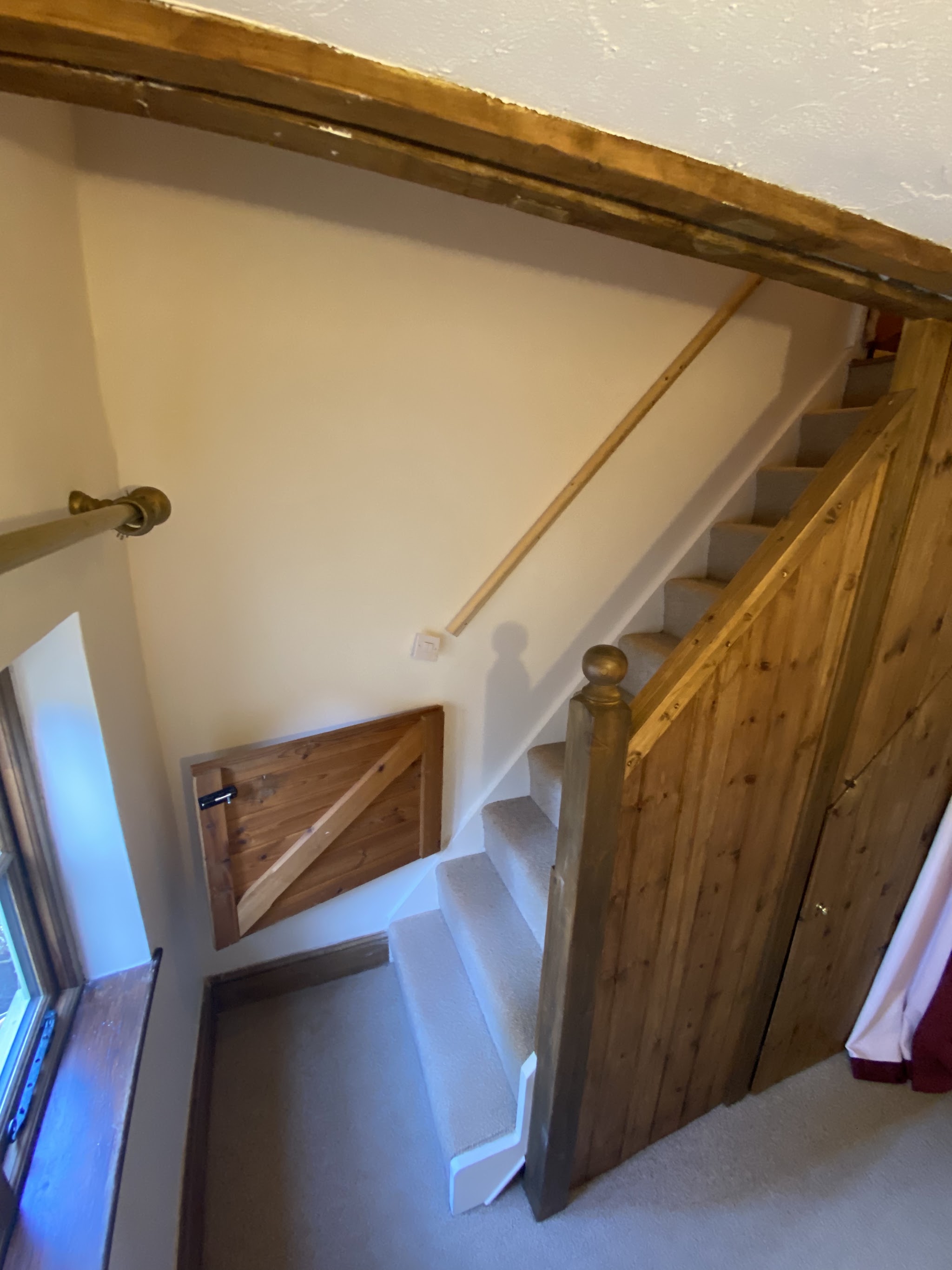 Cottage staircase with cream walls, white stair stringer and a wooden handrail
