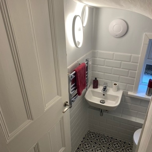 White cloakroom with metro tiles and a painted panelled door